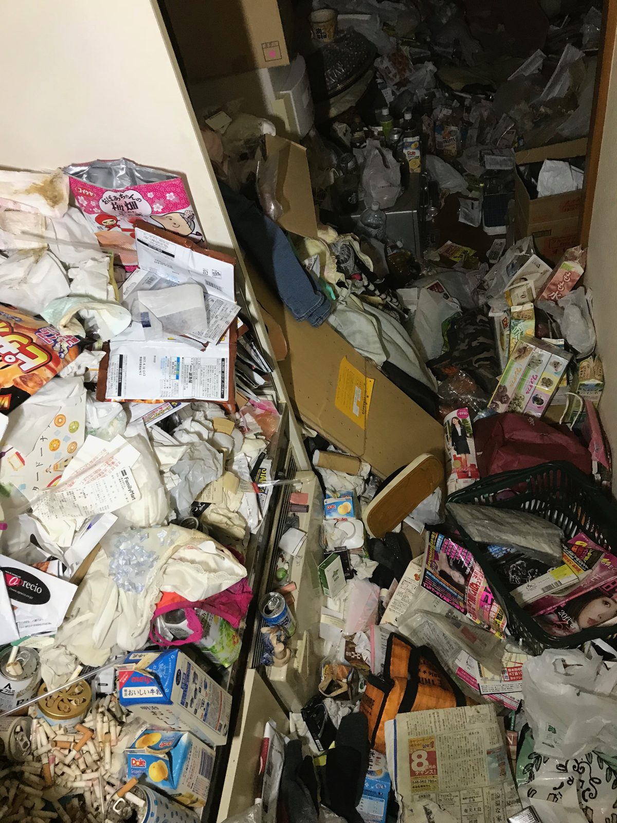 厚木市内で物があふれた部屋の片付け作業前。廊下から奥まで袋や空き箱、新聞、衣類が床を覆っている