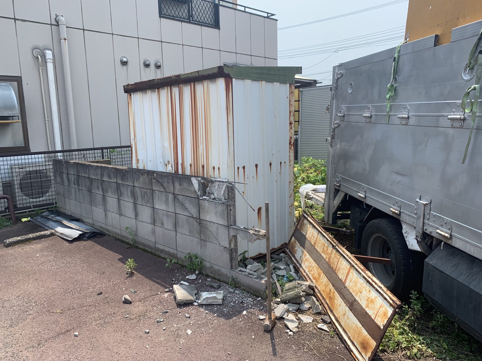 厚木市妻田西の外板に錆が広がり扉の板が外れた物置