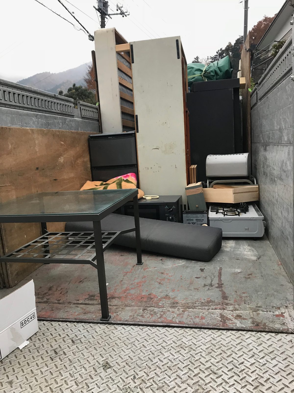 厚木市旭町でトラックの荷台に積んだガラス天板のテーブル、白い棚、黒い収納家具、ガスコンロ