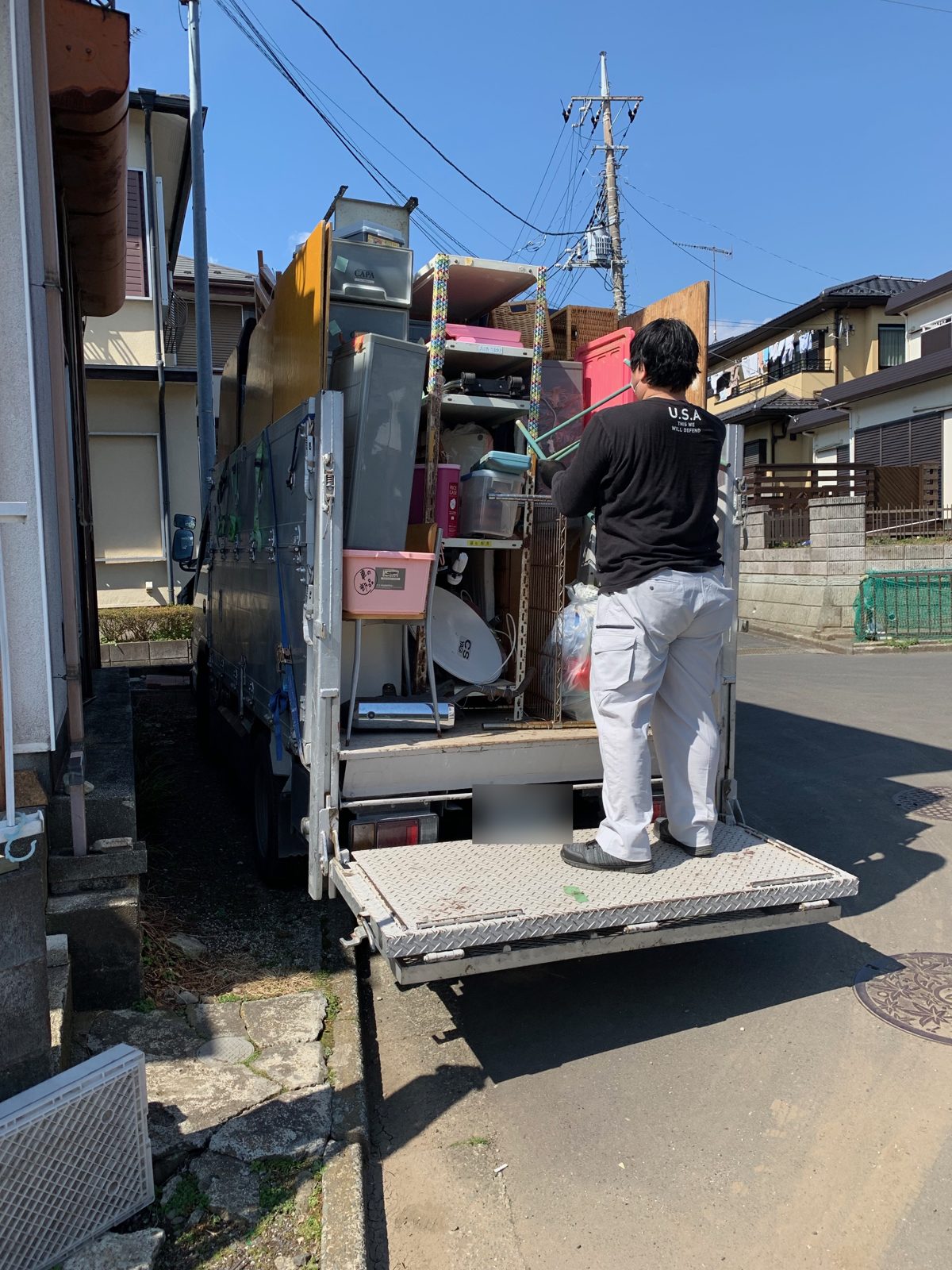 厚木市上荻野で昇降板付きの2トントラックにスタッフがスチール棚などを積み込んでいる様子